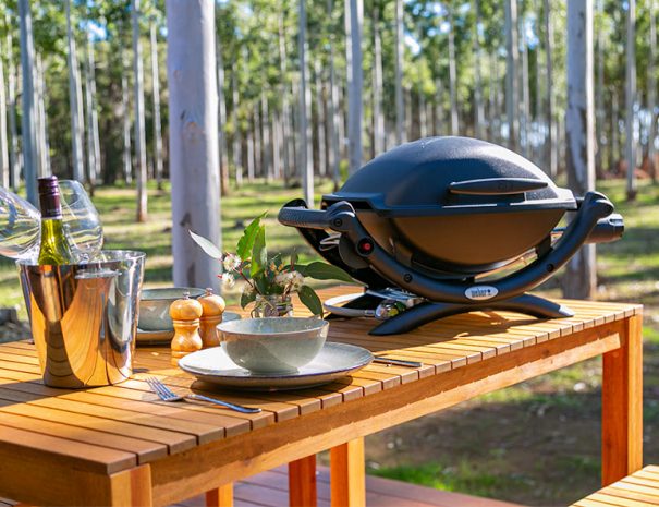 A weber BBQ on a table setting.