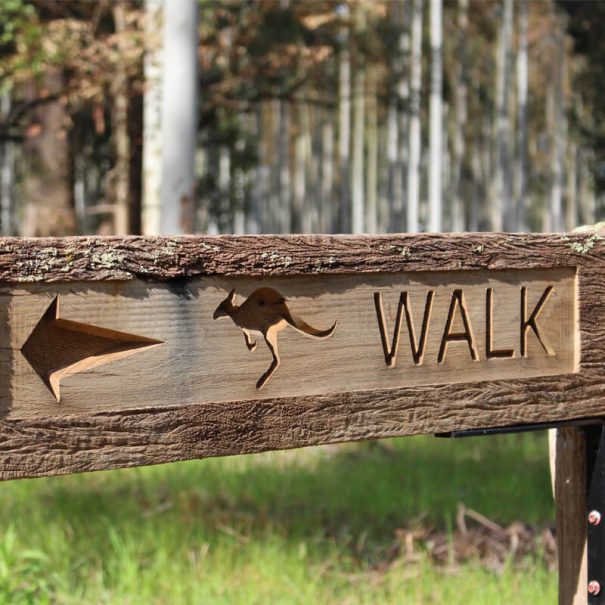 A wooden sign on a walk train with the words 'walk' There is a picture of a kangaroo on the sign.