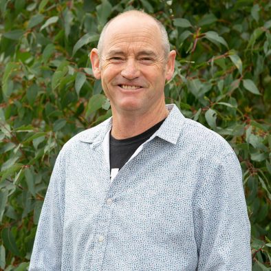 A man standing in front of a tree and smiling. He is one of the owners of Tree Chalets