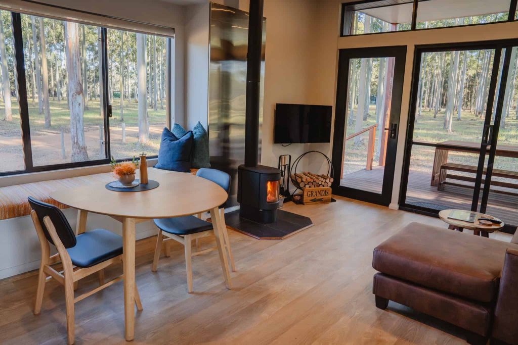 Eco-inspired living room in Chalet Grandis at Tree Chalets, showcasing natural textures and large windows overlooking the forest.