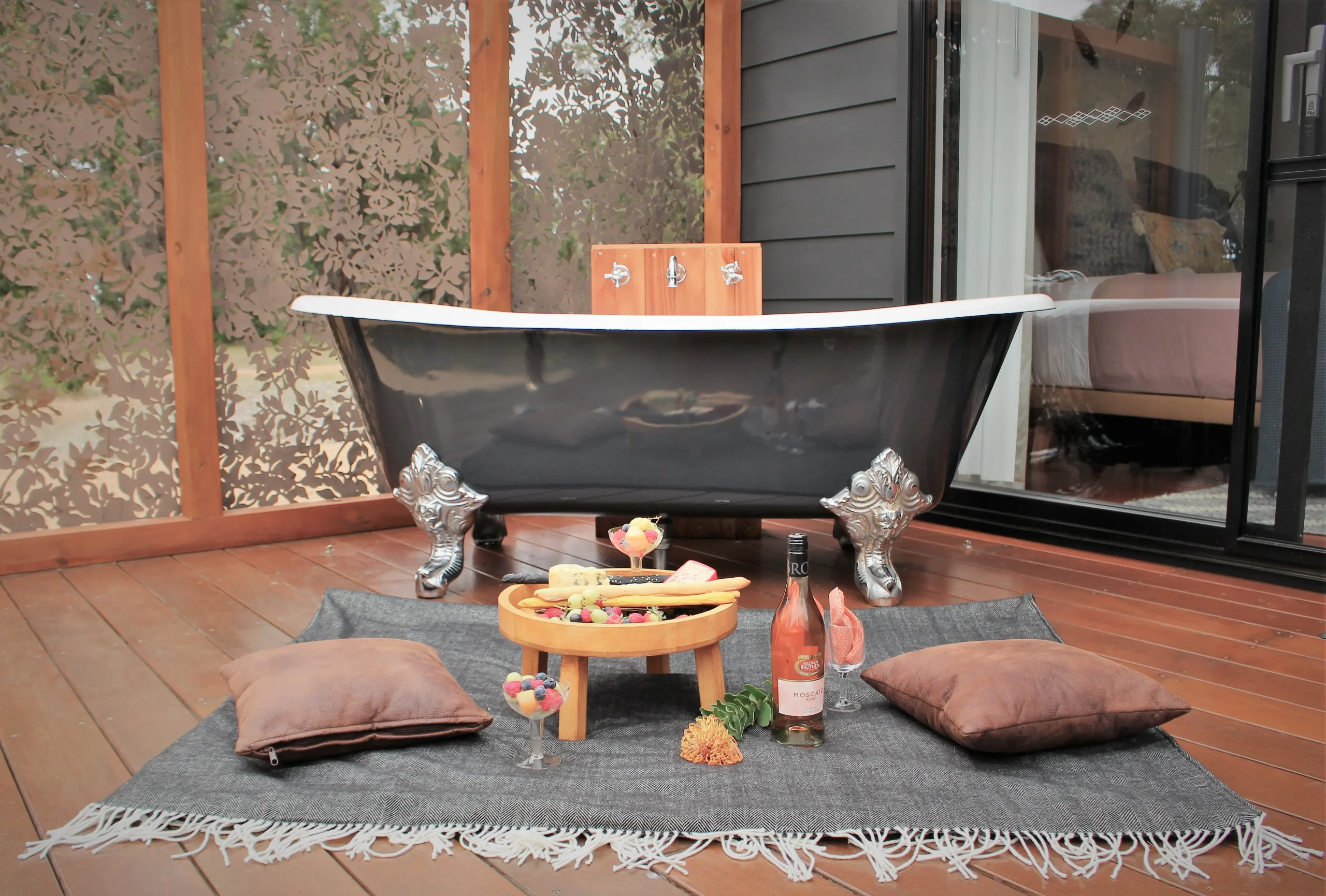 An outdoor bath with a picnic rug and grazing board in the foreground